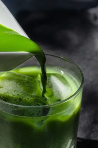 a pitcher pouring green liquid into a glass