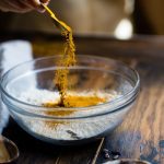 person pouring seasonings on clear glass bowl